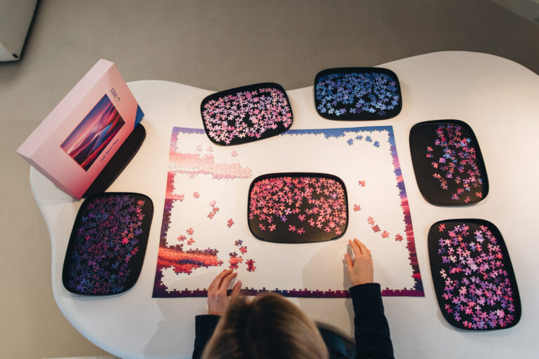Zwarte sorteerbakken met puzzelstukjes rond een puzzel